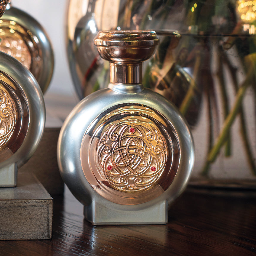 Real-life shot of the Resplendent perfume bottle in silver with rose gold detailing and three diamonds, capturing its luxurious design.